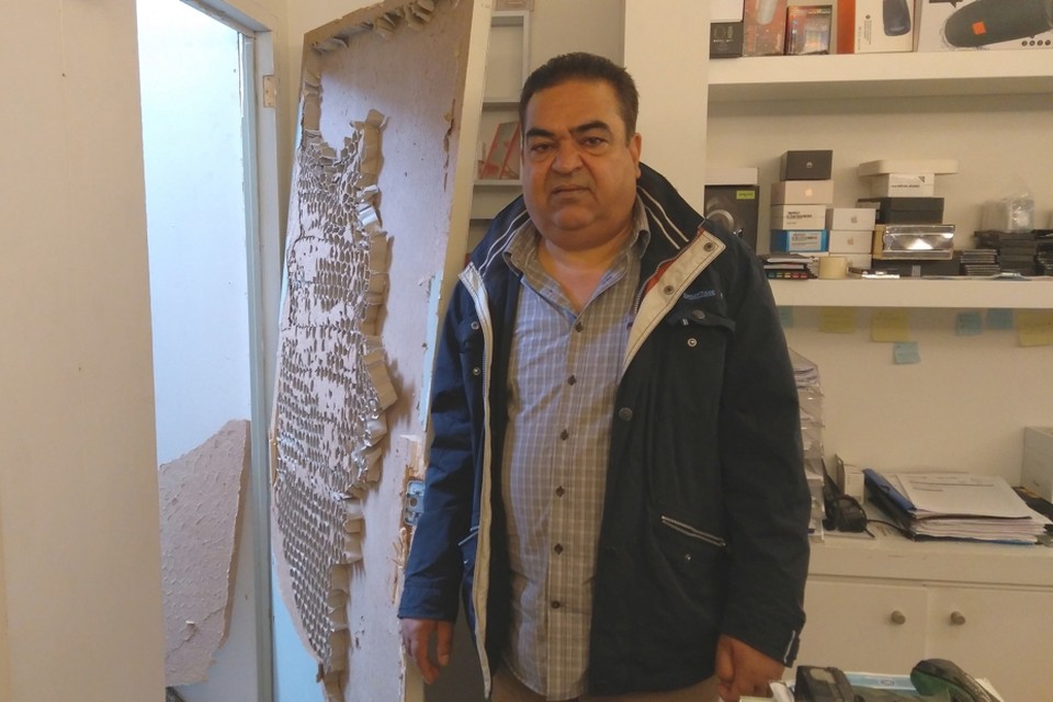 Bahaoddin Gholam toont de binnendeur die de inbreker volledig vernielde om in de winkel te kunnen komen.