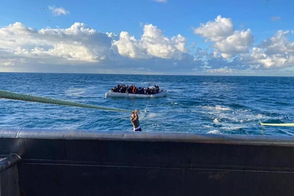 Een migrant probeert via een vislijn aan boord te klimmen. Een Nederlandse vissersboot redde woensdag zo’n dertig migranten op het Kanaal.  