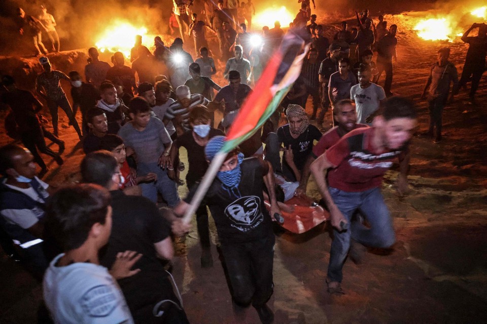 Palestijnen brengen een gewonde betoger in veiligheid tijdens een nachtelijk protest in de Gazastrook.