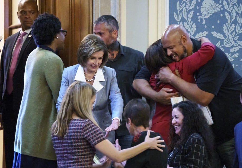 Nancy Pelosi (centraal) tussen verheugde nabestaanden en politieagenten.