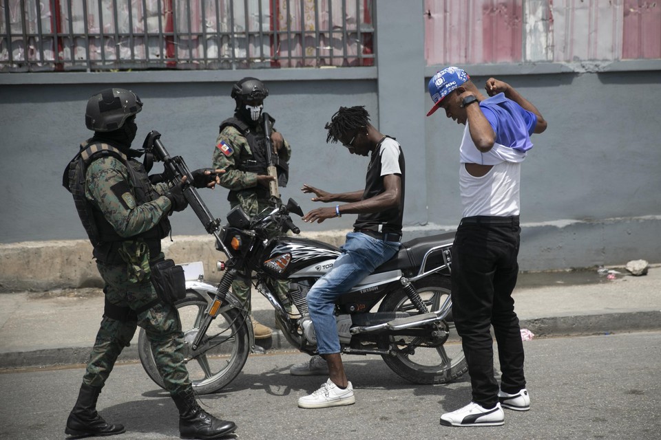 De ordediensten controleren twee mannen op wapens in Port-au-Prince. 