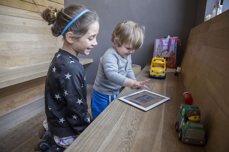 Tienjarig meisje en 1-jarige jongen vermaken zich samen met de iPad 
