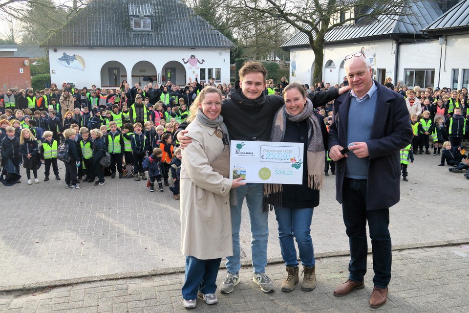 Sebastiaan en Stien van Ferm’Eline met juf Gitte en Sint-Ludgardis-directeur Eddy Smedts. Op de achtergrond staan de 725 leerlingen klaar om op sponsortocht te vertrekken.