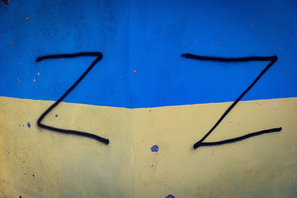 Russen schilderden het Z-symbool também oorlogsteken op een muur com o vlag Oekraïense. 
