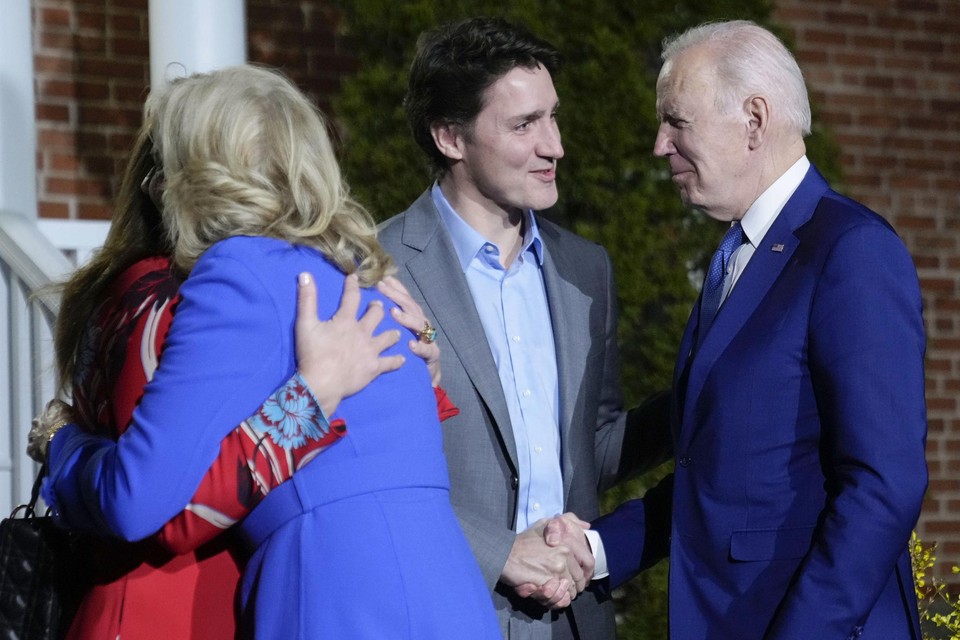 Biden schudt de hand met Trudeau, terwijl de first ladies elkaar begroeten.