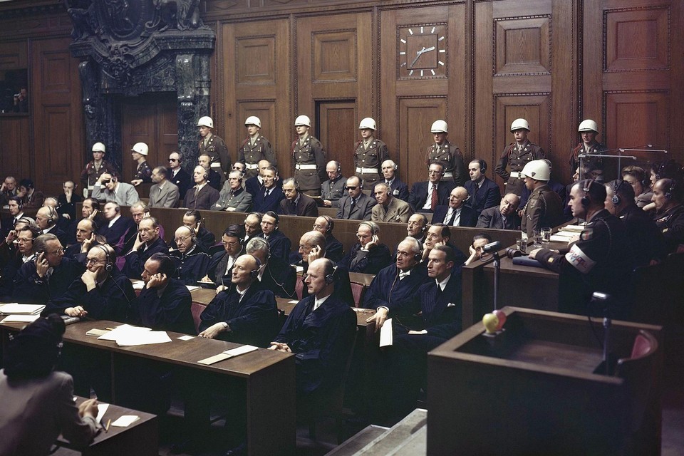 De rechtszaal met de wandklok en bewakers achter de beklaagdenbank. Links onderuitgezakt in die bank opper-nazi Hermann Göring. 