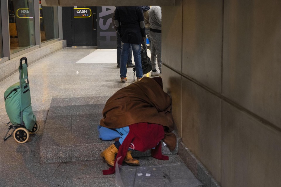 Een persoon slaapt op de grond in het station Brussel-Zuid. 