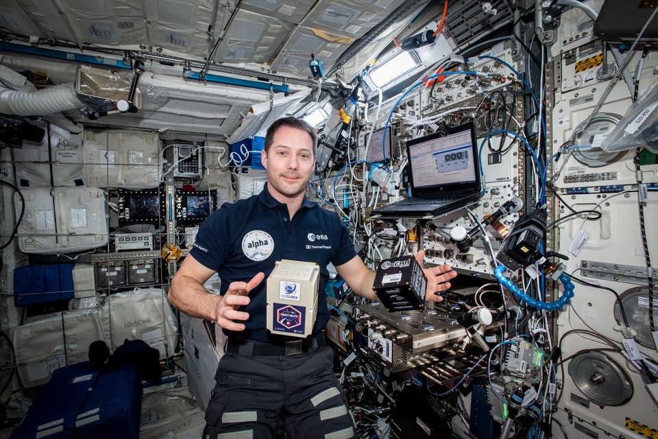 ESA-astronaut Thomas Pesquet poseert met de OSCAR-QUBE (zwarte kubus rechts) van de UHasselt in het ISS.