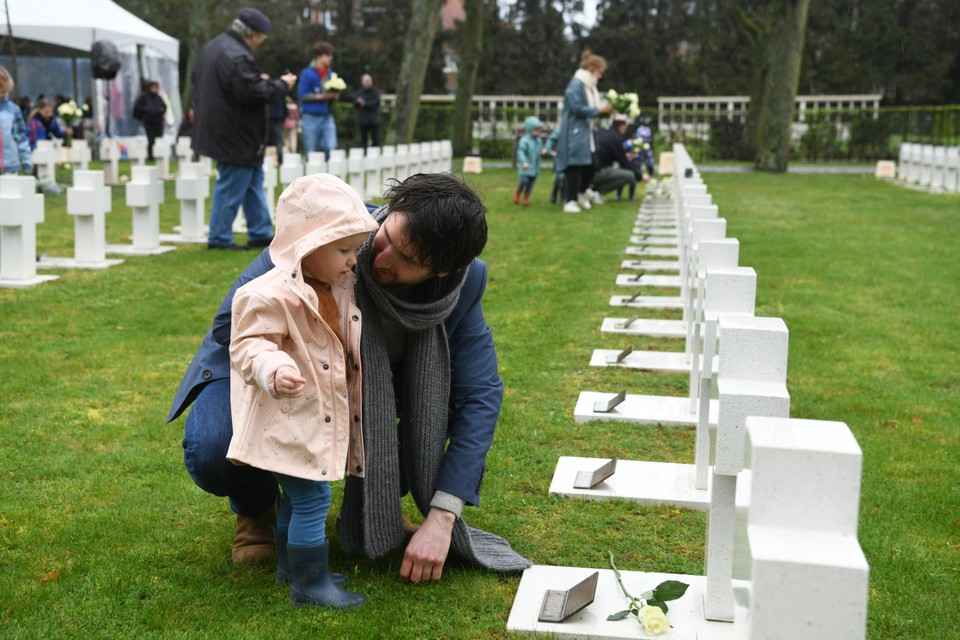 Historicus Pieter Serrien legt met zijn dochtertje een bloem neer bij het graf van een slachtoffer.