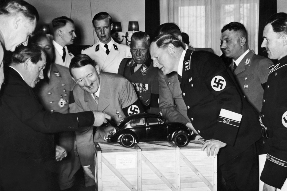 Nazileider Adolf Hitler bewondert een model van de VW Kever. Ontwerper Ferdinand Porsche (links) toont hem waar de motor zit. 