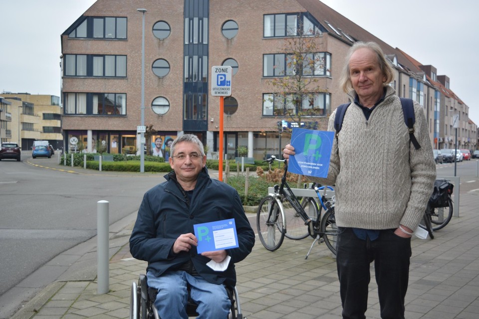 Schepenen Jan Tondeleir en Piet Van Heddeghem tonen de parkeerzorgsticker die voortaan aangevraagd en afgehaald kan worden.