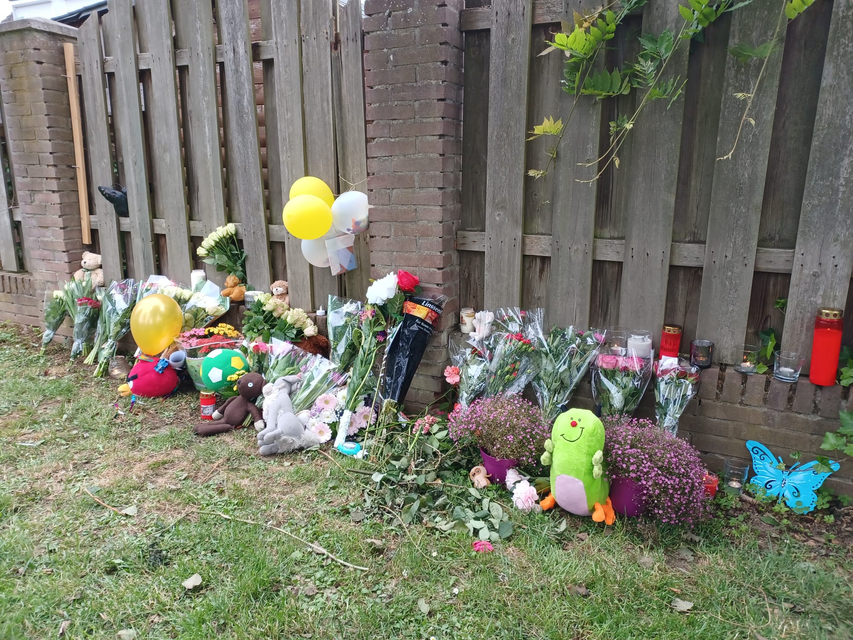 Bloemen, ballonnen en knuffels aan het hek van de tuin waar Gino gisteren gevonden werd 