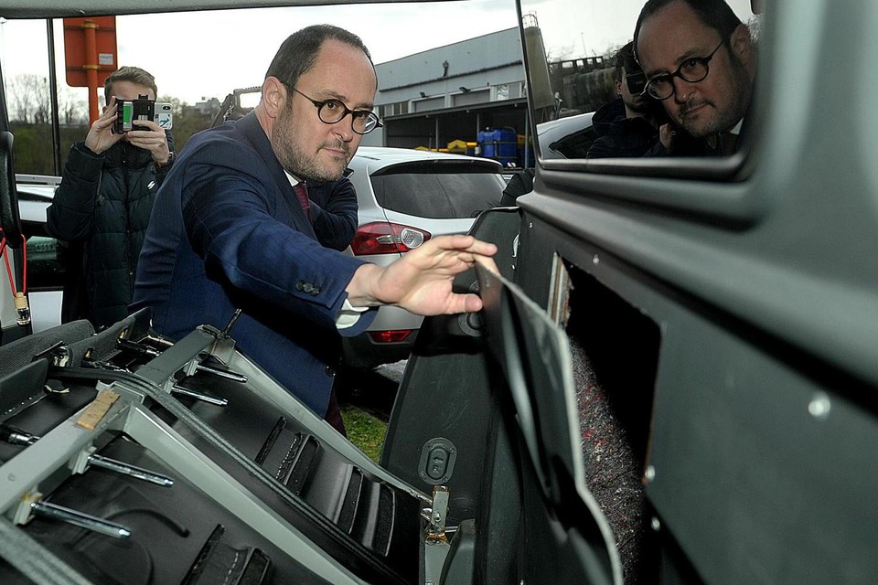 Minister Van Quickenborne bekijkt een verborgen ruimte achter een passagierszetel.