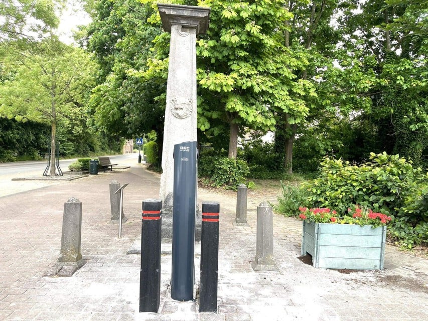At the front of the charging station and just behind the historical pillory.