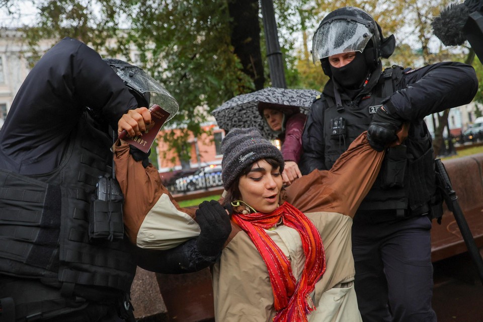 Russische politiemannen arresteren een protesterende vrouw in Moskou. 