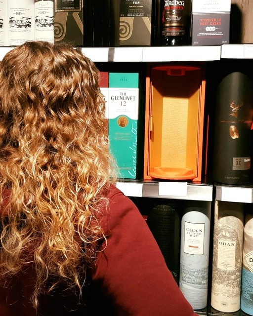 Een medewerkster van drankenhandel Daems in Lille staat bij het rek met het lege kistje van de gestolen fles whisky van 160 euro. 