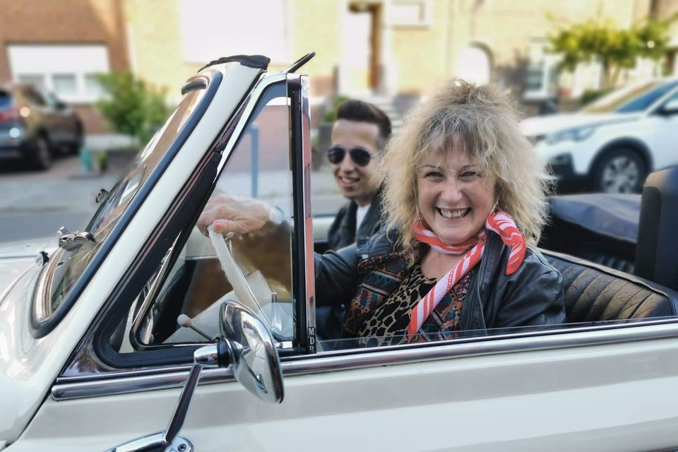Juf Nelly geniet aan het stuur van een oldtimer cabrio van het verrassingsafscheid in Grease-stijl, met naast haar een oud-leerling verkleed als Danny uit de filmhit. 