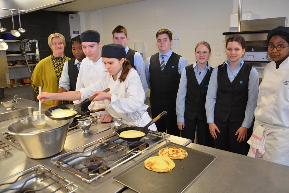 Directeur Katleen De Temmerman (links) moedigt de leerlingen van 3 Restaurant-keuken aan bij het bakken van honderden pannenkoeken.