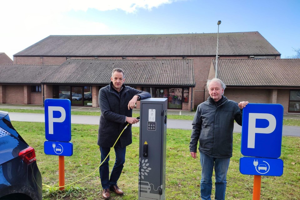 Schepenen Van Elsacker en De Cordt bij een laadpaal voor elektrische wagens. 