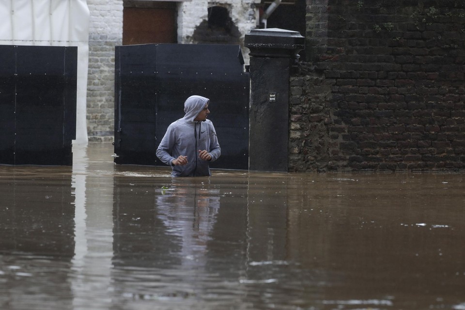 Een inwoner van Verviers waadt door het water dat het hele stadje overspoeld heeft.  