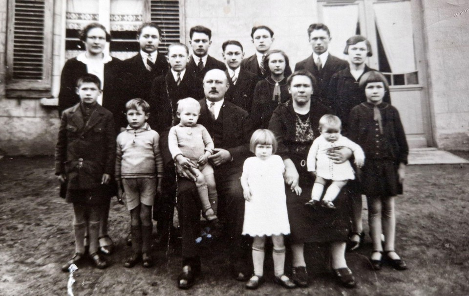 Marcel (links naast het kind op de schoot van zijn vader) met zijn ouders, broers en zussen.